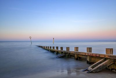 Pier over sea against sky during sunset