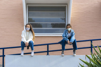 Full length portrait of woman sitting on railing