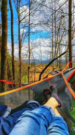 Low section of man relaxing on hammock in forest