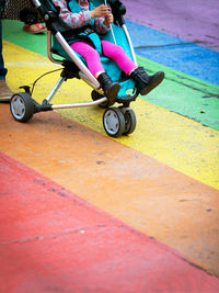 Low section of toddler sitting on baby stroller