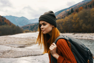 Portrait of beautiful woman standing against mountains