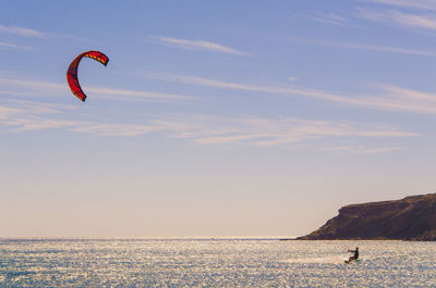 Person kiteboarding in sea against sky