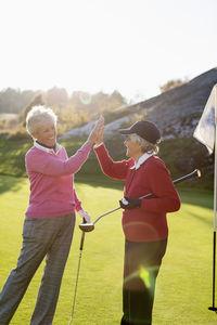 Happy senior female golfers giving high-five on golf course