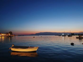 Sailboats moored in marina at sunset