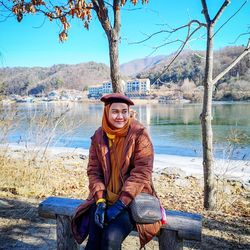 Woman sitting against lake during winter