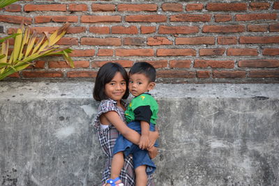 Full length of mother and daughter against wall