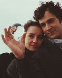 Couple looking at crystal ball against sky