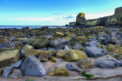 Rocks on sea shore against sky