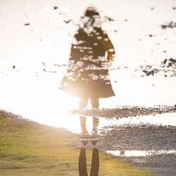 Rear view of woman standing by sea against sky