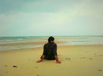 Rear view of a man overlooking calm beach