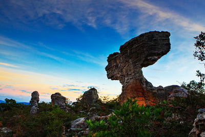 Rock formations on landscape against cloudy sky