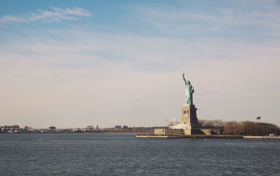 Statue of liberty by hudson river against sky