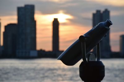 Close-up of coin-operated binoculars against orange sky during sunset