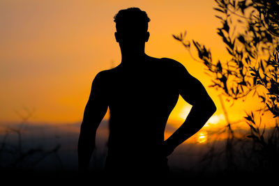 Rear view of silhouette man standing against sky during sunset