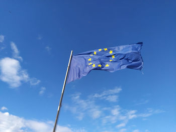 Low angle view of flag against blue sky