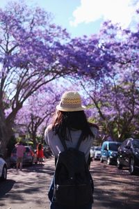 Rear view of woman with pink flowers against trees