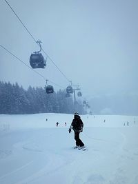 Overhead cable car on snow covered field against sky