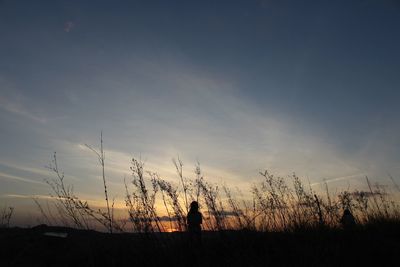 Silhouette of person standing on field against sky during sunset