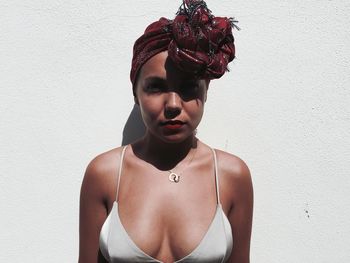 Portrait of seductive woman standing against wall during sunny day
