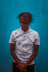 Portrait of a young man standing against blue wall