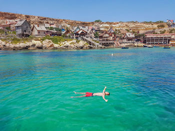 People swimming in sea against buildings