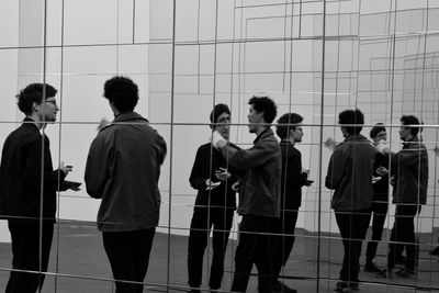 Rear view of people standing against wall