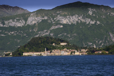 Scenic view of sea by mountain against sky