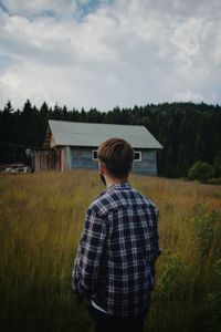 Rear view of man standing on field against sky