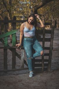 Full length of young woman standing by wood