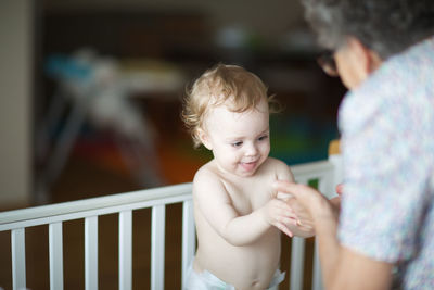 A senior woman between 70 and 80 years old is playing with her granddaughter of one year