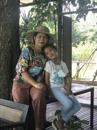 Portrait of mother and girl sitting on tree