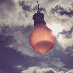 Low angle view of illuminated light bulb against sky