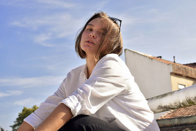 Low angle view of woman sitting against sky