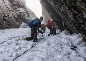 Rear view of people walking on snow covered mountain