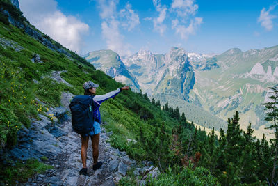 Rear view of man looking at mountains against sky