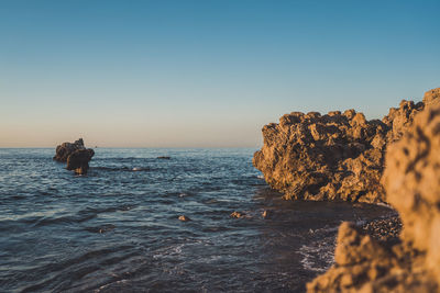 Scenic view of rocks in sea against clear sky