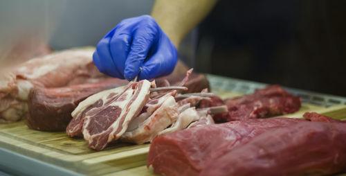 Taking a lamb cutlet from a showcase with meat