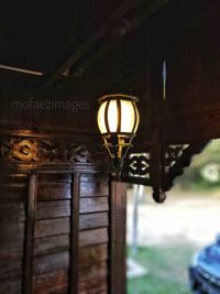 Close-up of illuminated electric lamp hanging on old building