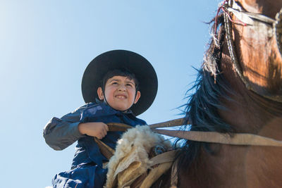 Low angle view of boy wearing hat against sky