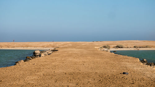 Walkway leading towards beach against sky