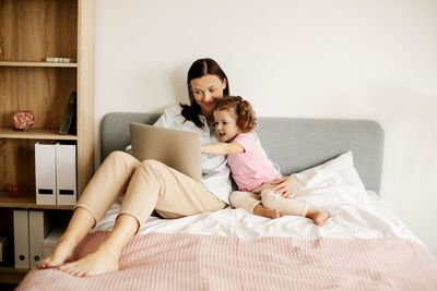 A sweet mom with her little daughter watches a video or movie on a laptop, or works from home