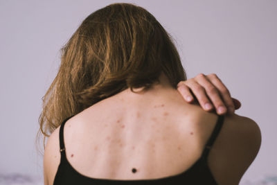 Rear view of young woman standing against white background