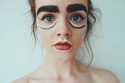 Portrait of teenage girl with face paint against wall