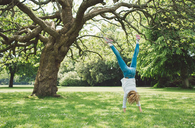 Woman doing handstand on grassy field