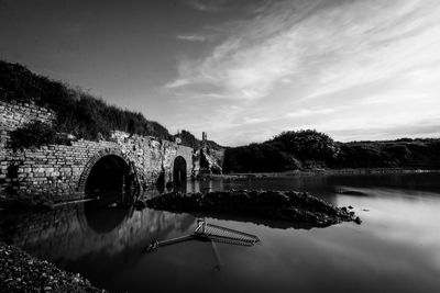 Arch bridge over lake against sky