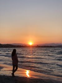 Woman standing on beach during sunset