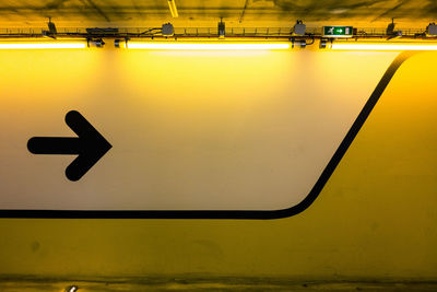 Black arrow symbol on illuminated yellow wall