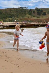 Rear view of mother and daughter walking at beach