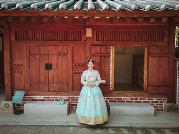 Portrait of woman standing against building