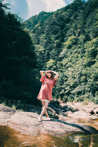 Woman standing by tree against mountain